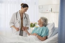 Médico y paciente mayor hablando en la habitación del hospital - foto de stock