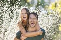 Couple playing in sprinkler in backyard — Stock Photo