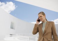 Улыбающаяся деловая женщина разговаривает по мобильному телефону во дворе — стоковое фото