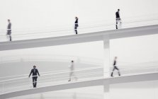Gente de negocios borrosa caminando por pasarelas elevadas - foto de stock