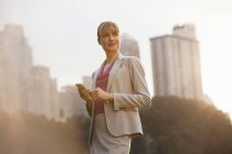 Businesswoman using cell phone in urban park — Stock Photo