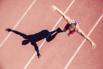 Track and field athlete jumping on track with arms outstretched — Stock Photo