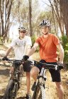 Dos ciclistas de montaña en el camino de tierra en el bosque - foto de stock