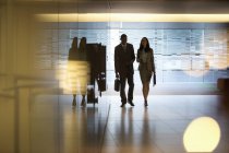 Hombre de negocios y mujer de negocios caminando en el vestíbulo en la oficina moderna - foto de stock