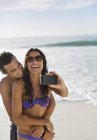 Couple heureux prenant autoportrait avec téléphone caméra sur la plage — Photo de stock