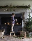 Vista lateral do menino bonito decorar lareira de Natal — Fotografia de Stock