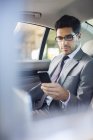 Empresário usando telefone celular no banco de trás do carro — Fotografia de Stock