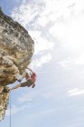 Низкий угол обзора альпиниста, поднимающегося по крутой скале — стоковое фото