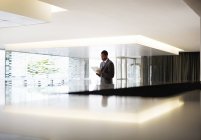 Silhouette eines Geschäftsmannes mit digitalem Tablet in der Lobby eines modernen Büros — Stockfoto