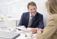 Smiling business people discussing paperwork in cafe — Stock Photo