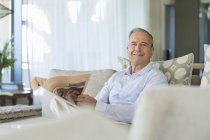 Älterer Mann liest Zeitung auf dem Sofa — Stockfoto