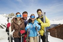Friends on mountain top holding skis together — Stock Photo