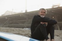 Surfista più anziano seduto con pensione sulla spiaggia — Foto stock