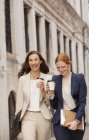 Улыбающиеся женщины ходят с кофе — стоковое фото