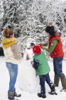Mère et enfants faisant bonhomme de neige à l'extérieur — Photo de stock