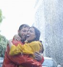 Feliz pareja caucásica abrazándose bajo la lluvia - foto de stock