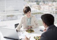 Businessman and businesswoman with laptop meeting over lunch — Stock Photo