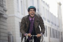 Захоплюючий бізнесмен їде на велосипеді під дощем — стокове фото