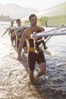 Squadra canottaggio che trasporta scull nel lago — Foto stock