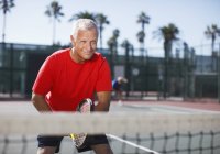 Пожилой человек играет в теннис на корте — стоковое фото