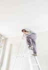 Homem caucasiano hábil escalada escada dentro de casa — Fotografia de Stock