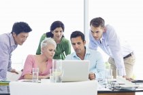 Деловые люди, использующие ноутбук на встрече в современном офисе — стоковое фото