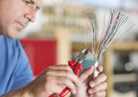 Skillful caucasian electrician trimming wires — Stock Photo