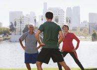 Older couple exercising with trainer in park — Stock Photo