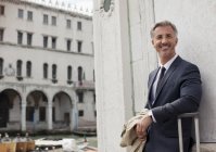 Retrato de un hombre de negocios sonriente con maleta en Venecia - foto de stock