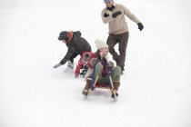 Familia activa feliz trineo en el campo cubierto de nieve - foto de stock