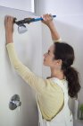 Mujer trabajando en la cabeza de la ducha en el baño - foto de stock