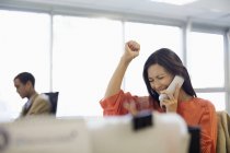 Businesswoman cheering at desk in office — Stock Photo
