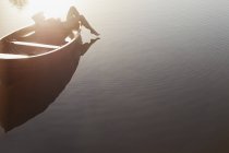 Жінка лежить у човні на сонячному озері — стокове фото