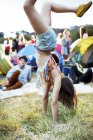 Woman doing handstand outside tents at music festival — Stock Photo