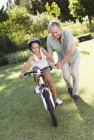 Homem mais velho ensinando neta a andar de bicicleta — Fotografia de Stock