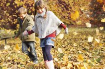Bambini felici che giocano in foglie di autunno — Foto stock