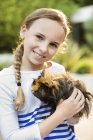 Smiling girl holding guinea pig outdoors — Stock Photo
