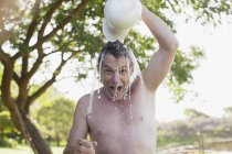 Retrato de homem entusiasta derramando água sobrecarga — Fotografia de Stock