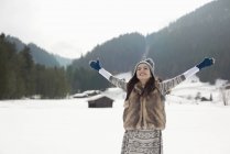 Беззаботная женщина с распростертыми руками в снежном поле — стоковое фото