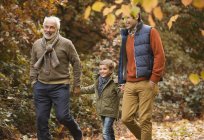 Tres generaciones de hombres caminando en el parque - foto de stock