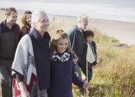 Famiglia sorridente multi-generazione che cammina sull'erba della spiaggia — Foto stock