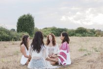 Boho women meditating in circle in rural field — Stock Photo