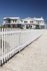 Белый забор для пикета, ведущий к пляжным домам — стоковое фото