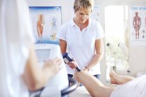 Фізичний терапевт використовує ультразвуковий зонд на нозі жінки? — стокове фото