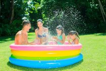 Family playing together in wading pool — Stock Photo