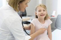 Pediatra che utilizza stetoscopio su paziente ragazza in sala d'esame — Foto stock