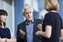 Senior businessman gesturing and talking to colleagues — Stock Photo