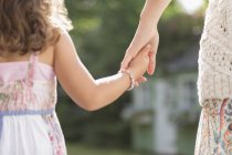 Крупним планом ззаду мати і дочка тримаються за руки — стокове фото