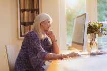 Mujer mayor que trabaja en la computadora en la oficina en casa - foto de stock