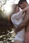Couple hugging by river — Stock Photo